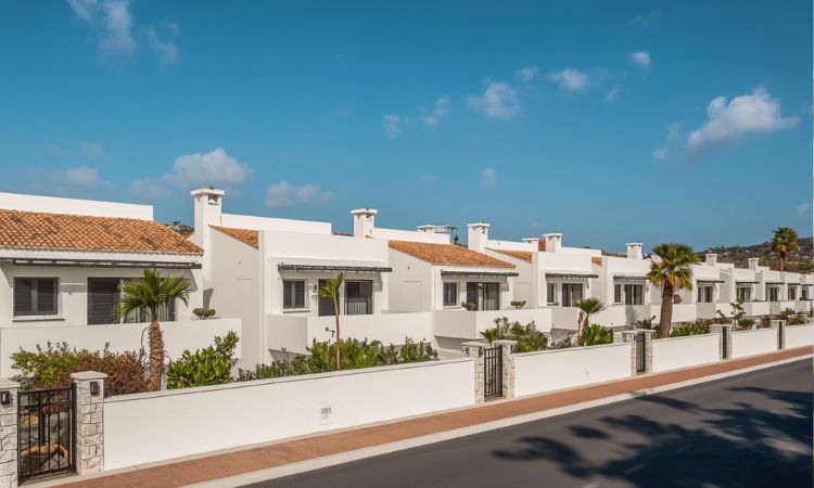 Modern luxury apartment overlooking the Mediterranean Sea in Manilva, featuring a private pool, palm trees, and panoramic coastal views.